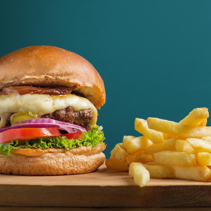 Image contexte Yami, burger gourmand et frites posés sur une table en bois, sur fond bleu