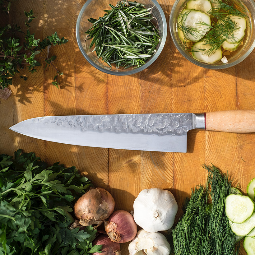 Image contexte Dessaint Traiteur, herbes, ail, oignon, couteau sur une plan de travail en bois