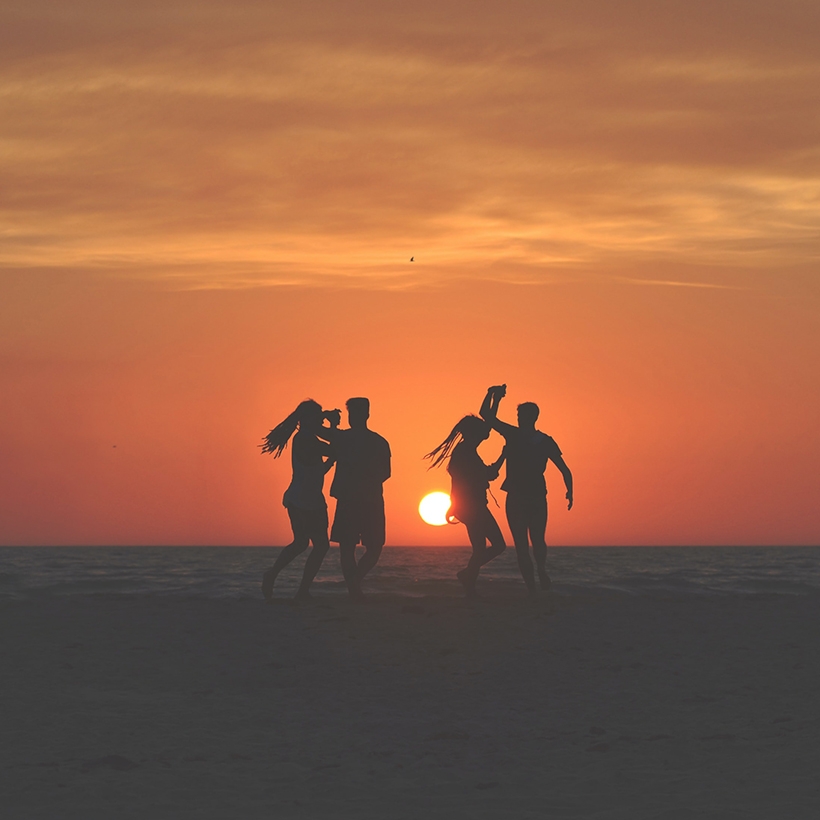 Image contexte Tropic Kiss, groupe de personnes qui dansent sur la plage, coucher de soleil