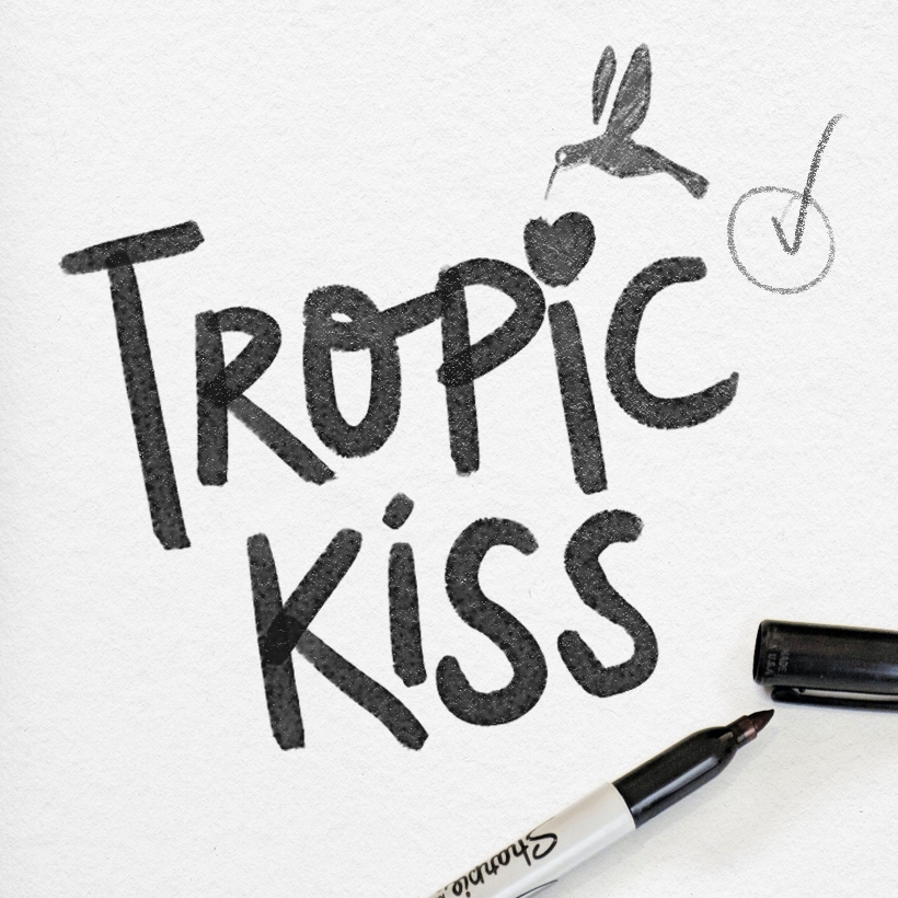 Esquisse logo Tropic Kiss, au crayon noir sur une feuille blanche, avec un crayon et son bouchon