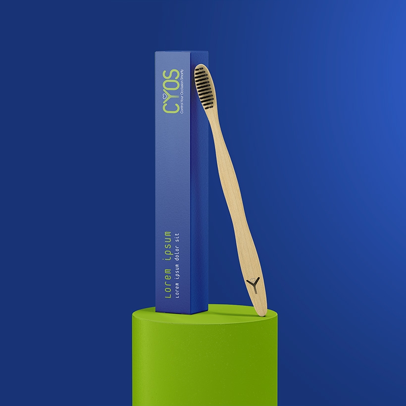Goodies CYOS, brosse à dent en bois, vue de face, sur un socle vert, packaging bleu, sur fond bleu