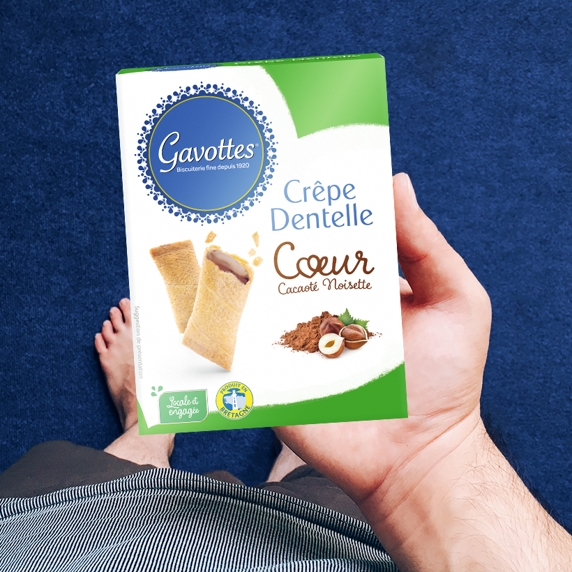Packaging boite de Gavottes Cœur cacao noisette, dans une main d’homme, sur fond bleu