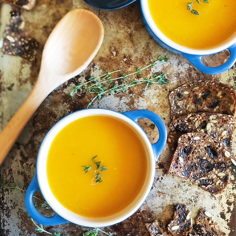 Photo culinaire soupe L’ile Bleue, sur un plan de travail, deux bols de soupe, avec une cuillère en bois et du pain, vue de dessus