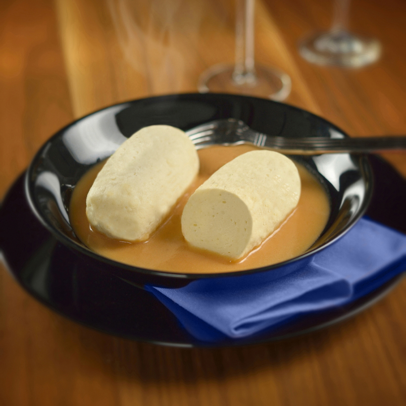 Photo culinaire Nolo Frères, quenelle dans une assiette, sur une table en bois, avec une serviette bleue en tissus 