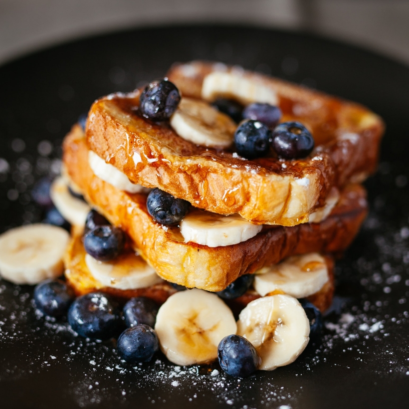 Image contexte Maison des sables, brioche perdue, avec banane, myrtilles et sirop d’érable, dans une assiette noire