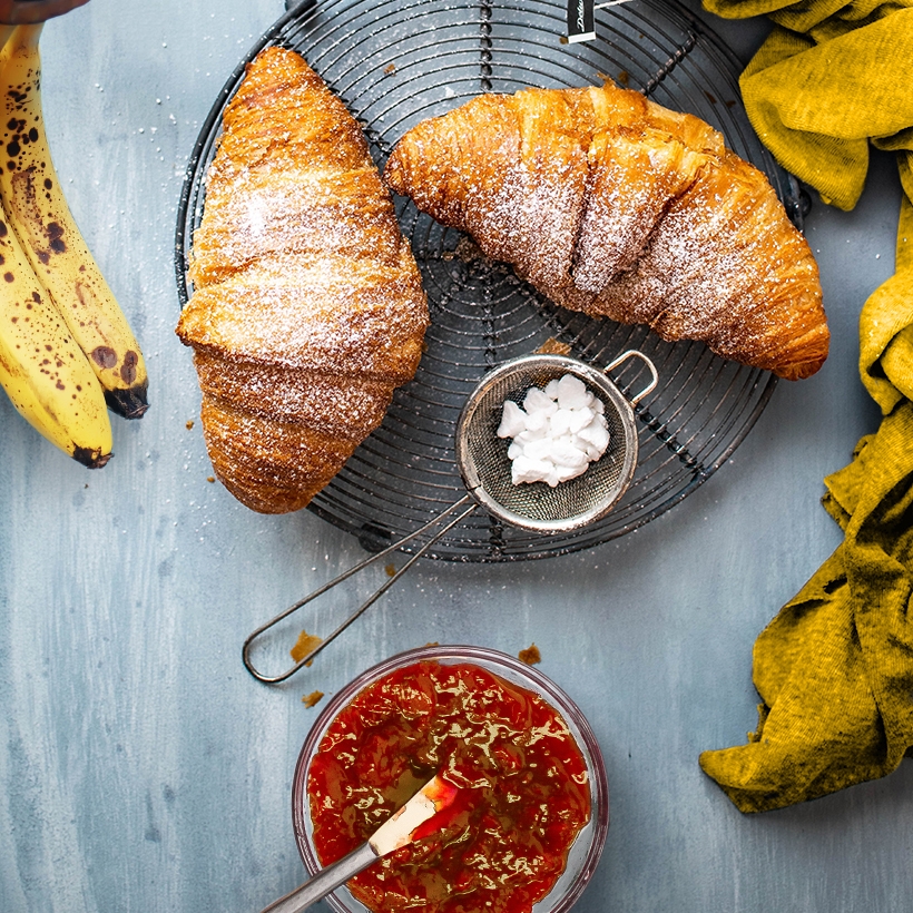 Image contexte M’amour Guy Lesueur ingrédients de petit déjeuner sur une table, croissants, confiture, banane, vue de dessus