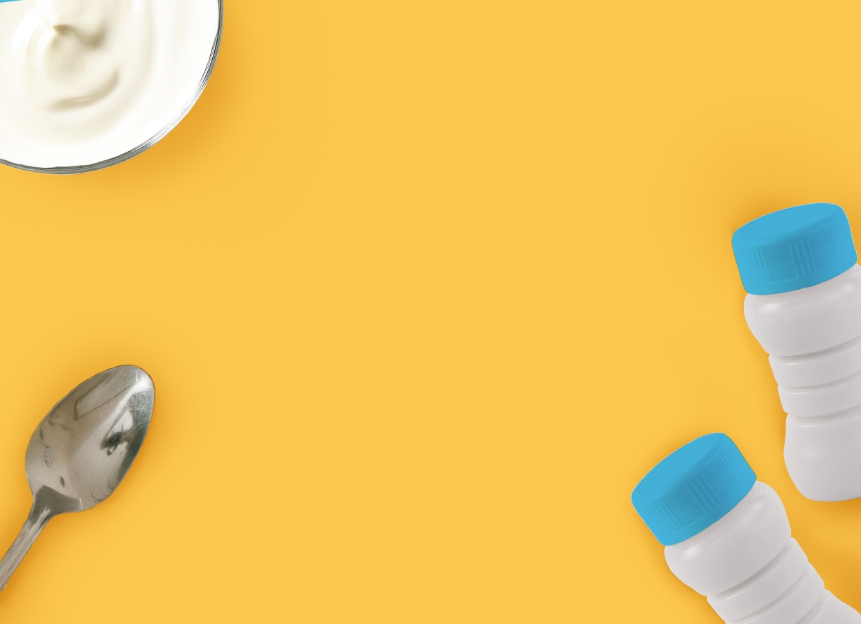 Image ambiance Laïta, bol de yaourt, petites bouteilles en plastique, cuillère en métal, sur fond jaune, vue de dessus
